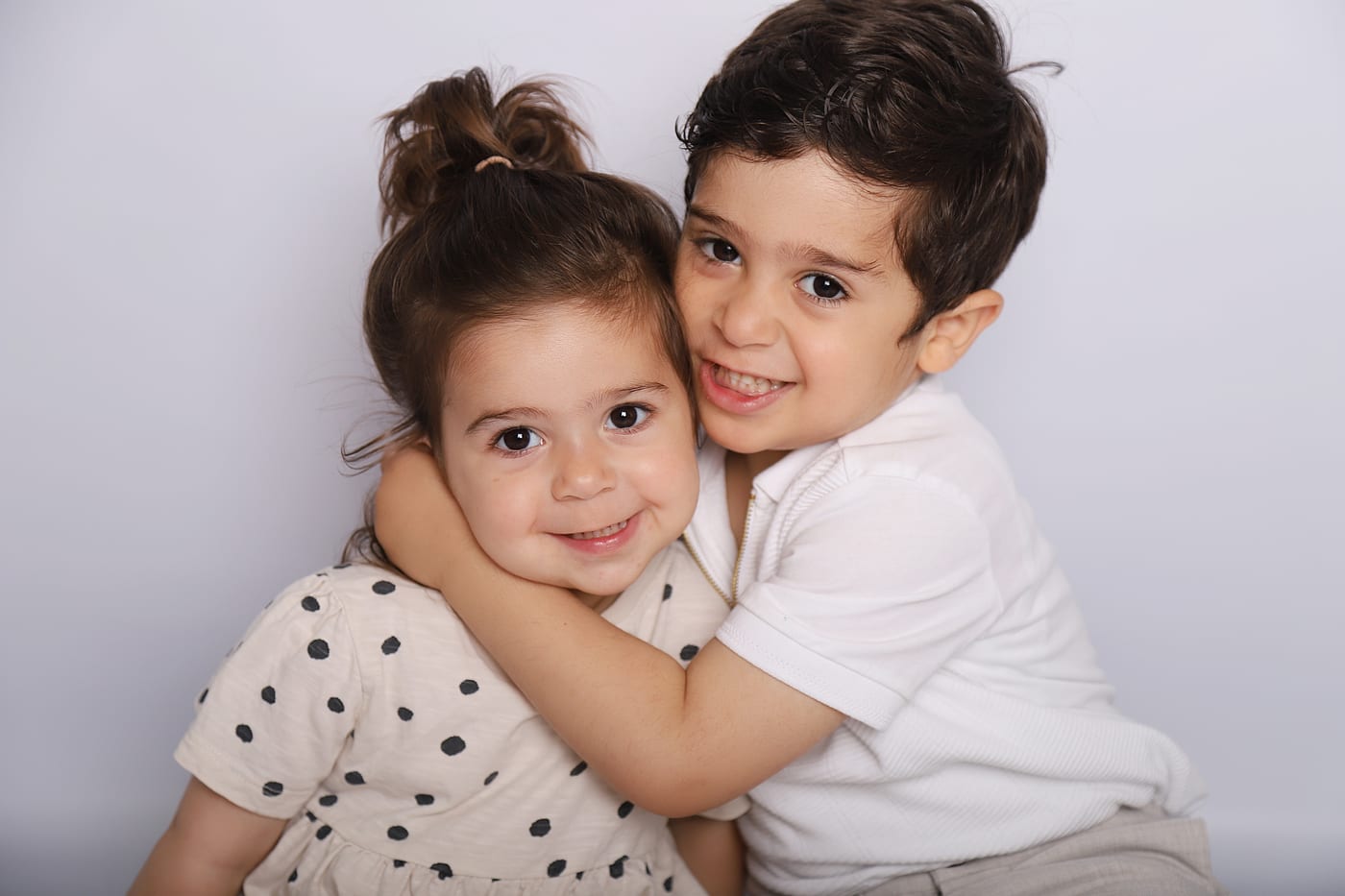 Two young children sharing a hug and smiling